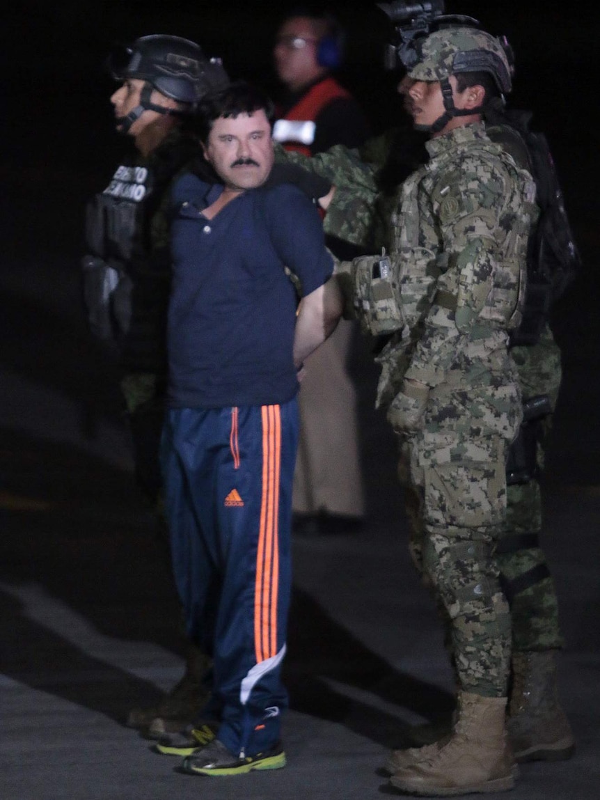Drug kingpin Joaquin "El Chapo" Guzman is escorted by marines to a helicopter at Mexico City's airport