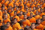 A large group of Buddhist monks wearing orange robes meditating