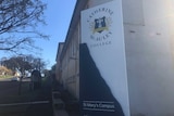 A sign with the catherine mcauley college logo sits outside the school