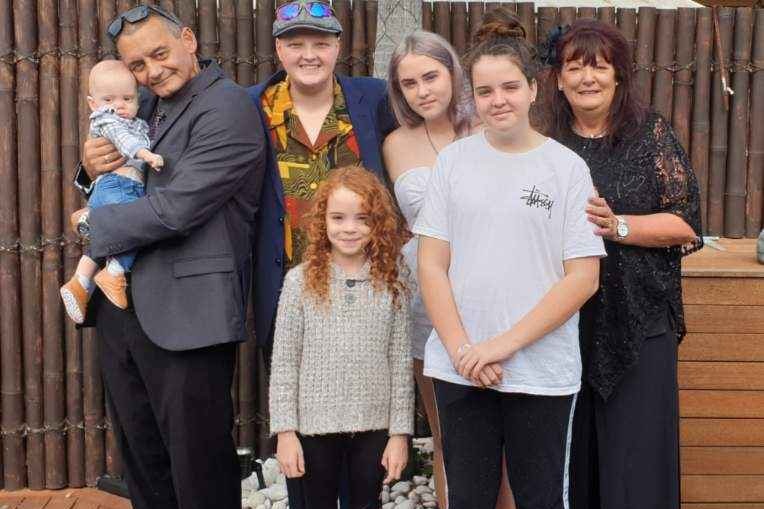 A group of siblings pose for a photo with their grandparents. 