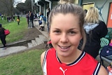 Katie Brennan in afl uniform smiling at football ground.