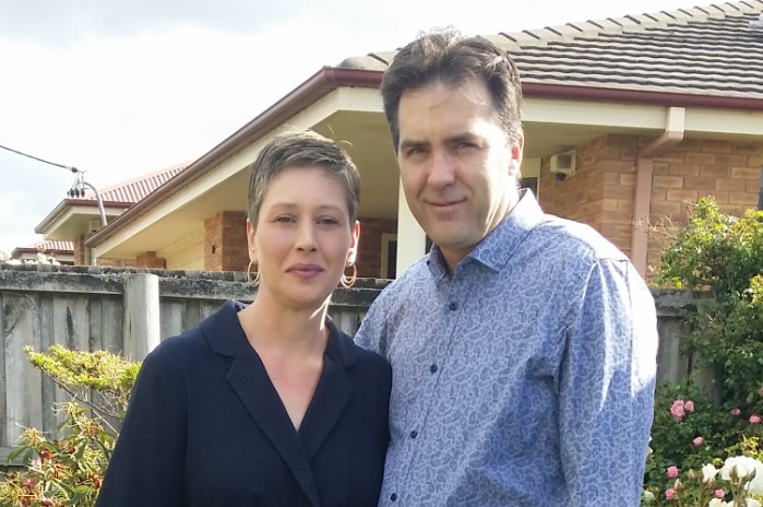 A couple poses for a photo in a yard