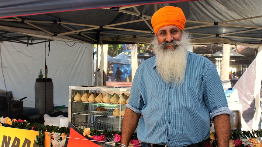 John Arkan standing in front of the food stall he operates each week at the Coffs Harbour Produce Markets.