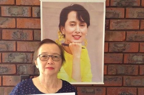 Khin Myo Myint poses with a portrait of Aung San Suu Kyi holding a poster for the National League for Democracy party.