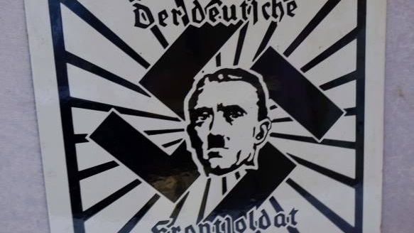 A Third Reich propaganda sign, with Adolf Hitler superimposed on a swastika.