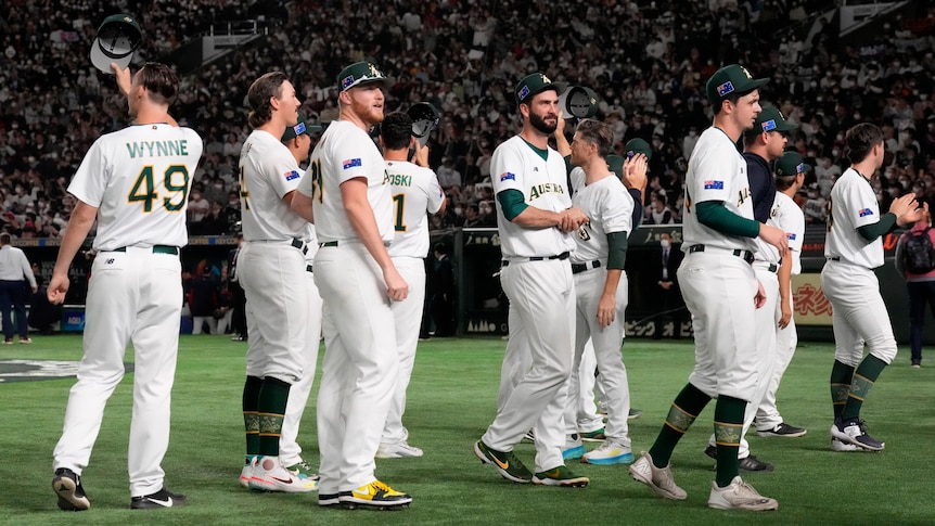 Australian men's baseball team wave goodbye to crowd after loss to home team Japan.