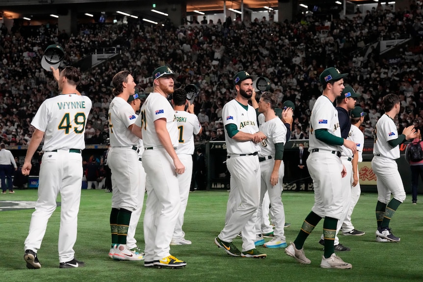 Australian men's baseball team wave goodbye to crowd after loss to home team Japan.