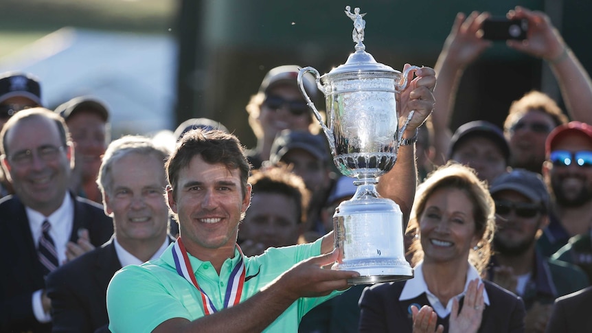Brooks Koepka holds the trophy after winning the US Open golf title at Erin Hills on June 18, 2017.