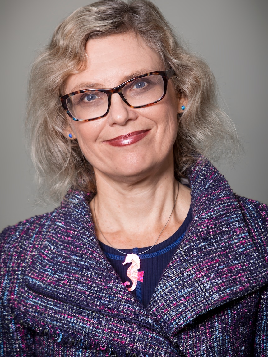 Portrait of Christine Parker, a mature aged woman with glasses and short blonde hair.