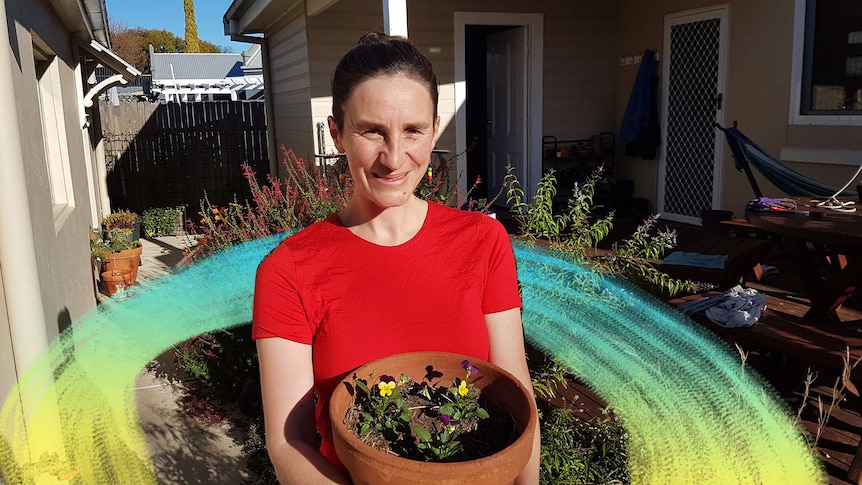 Alice Blackwood in the garden of her Bathurst home, holding a pot of pansies, she's planting more flowers during the pandemic.