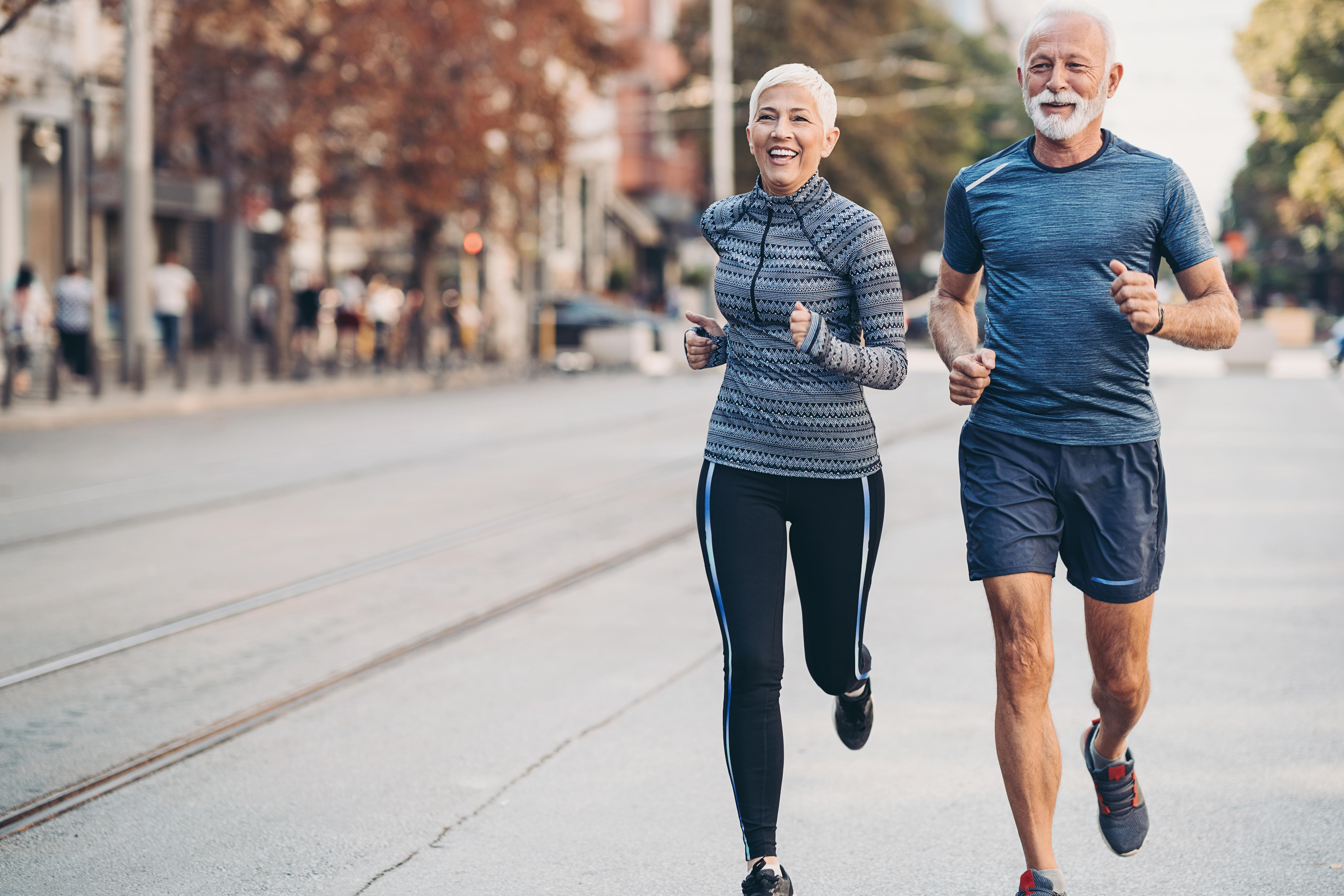 Older woman and man jogging in the street