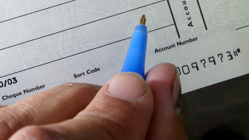 A close up of someone writing on a blank cheque