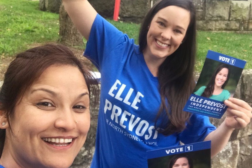 Elle Provost wearing a blue shirt with a campaign staffer in front of a marquee