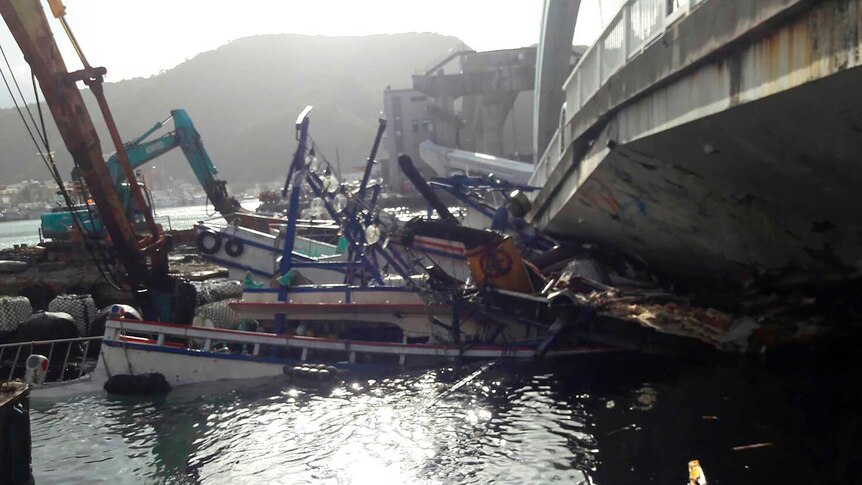 Crushed fishing boats lie under the collapsed bridge