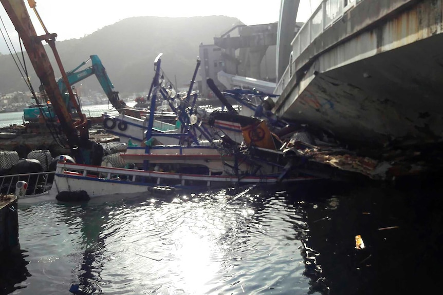 Crushed fishing boats lie under the collapsed bridge