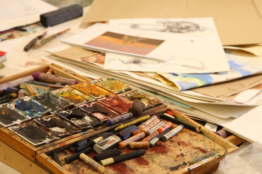 Water colours, crayons, chalk, paper and other art items on a table