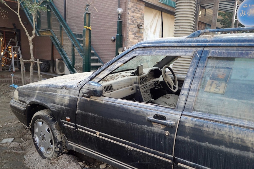 A car is covered in mud after being damaged by flooding.