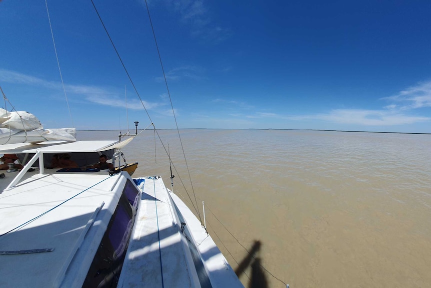 A photo of a boat on murky river water in the afternoon sun.