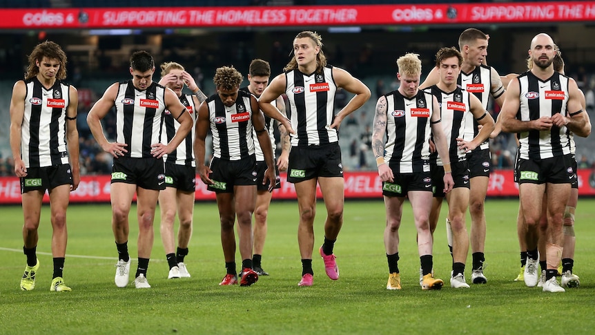 A group of Collingwood AFL players walk off the MCG.