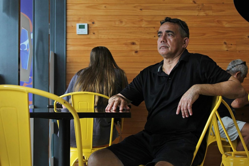 A photo of a business owner sitting in his cafe.