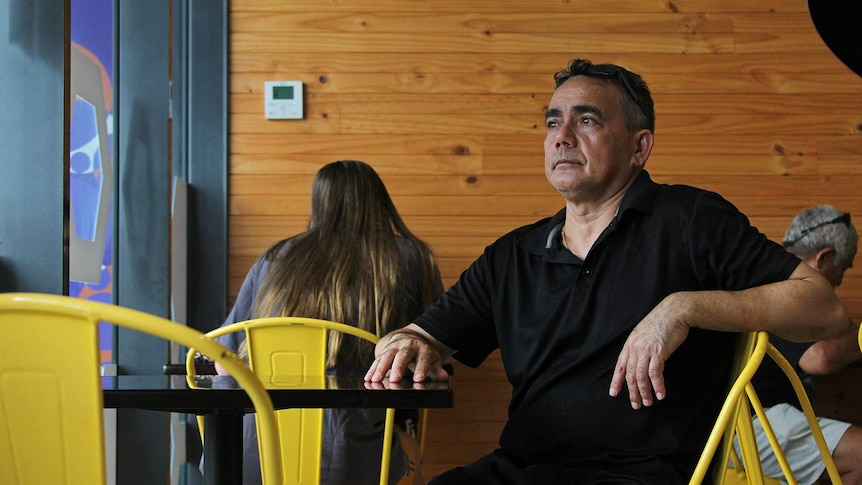 A photo of a business owner sitting in his cafe.