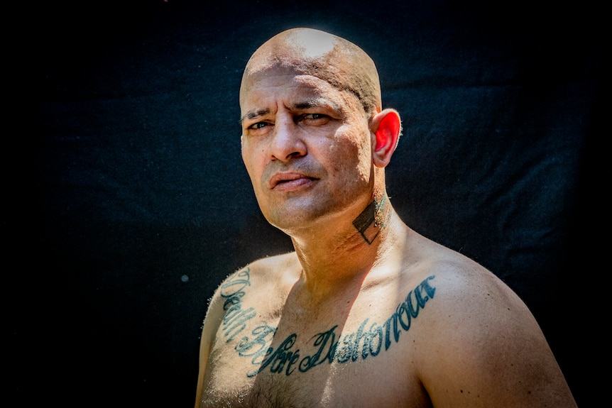 Shirtless man with a tattoo across his chest.