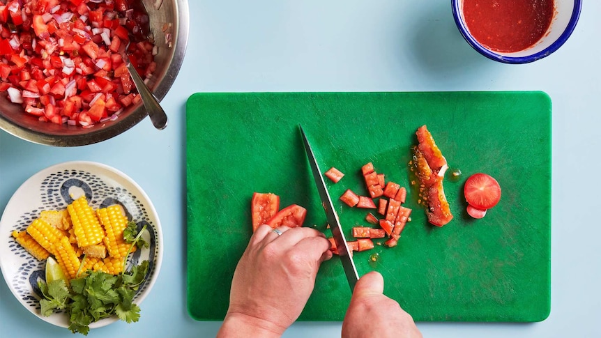 Salad salsa with tomatoes, corn and chips in preparation with tomato on chopping board