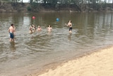 people in a creek playing with a ball 