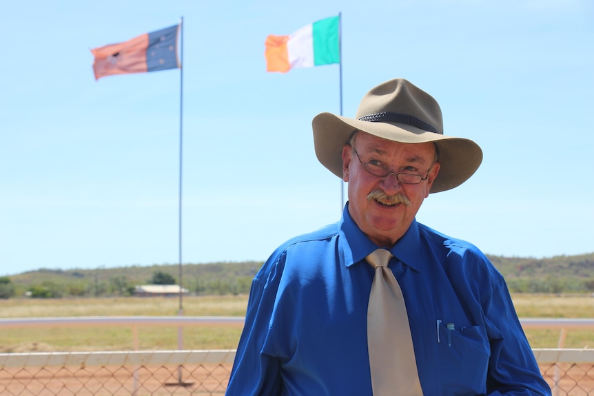Mike Nash stands in front of the Irish and Northern Territory flags.