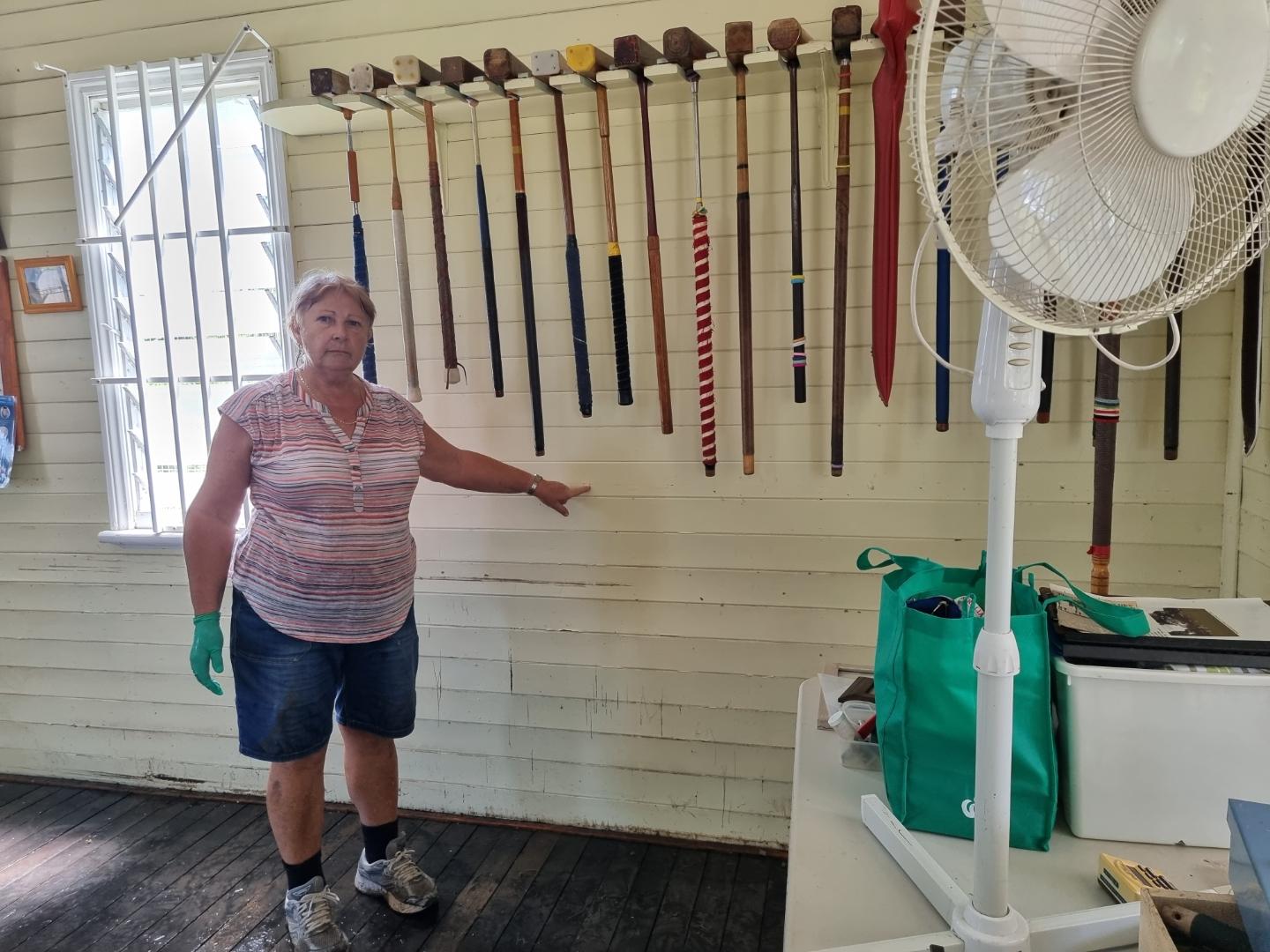 A woman stands in a building indicating the high watermark of a flood.