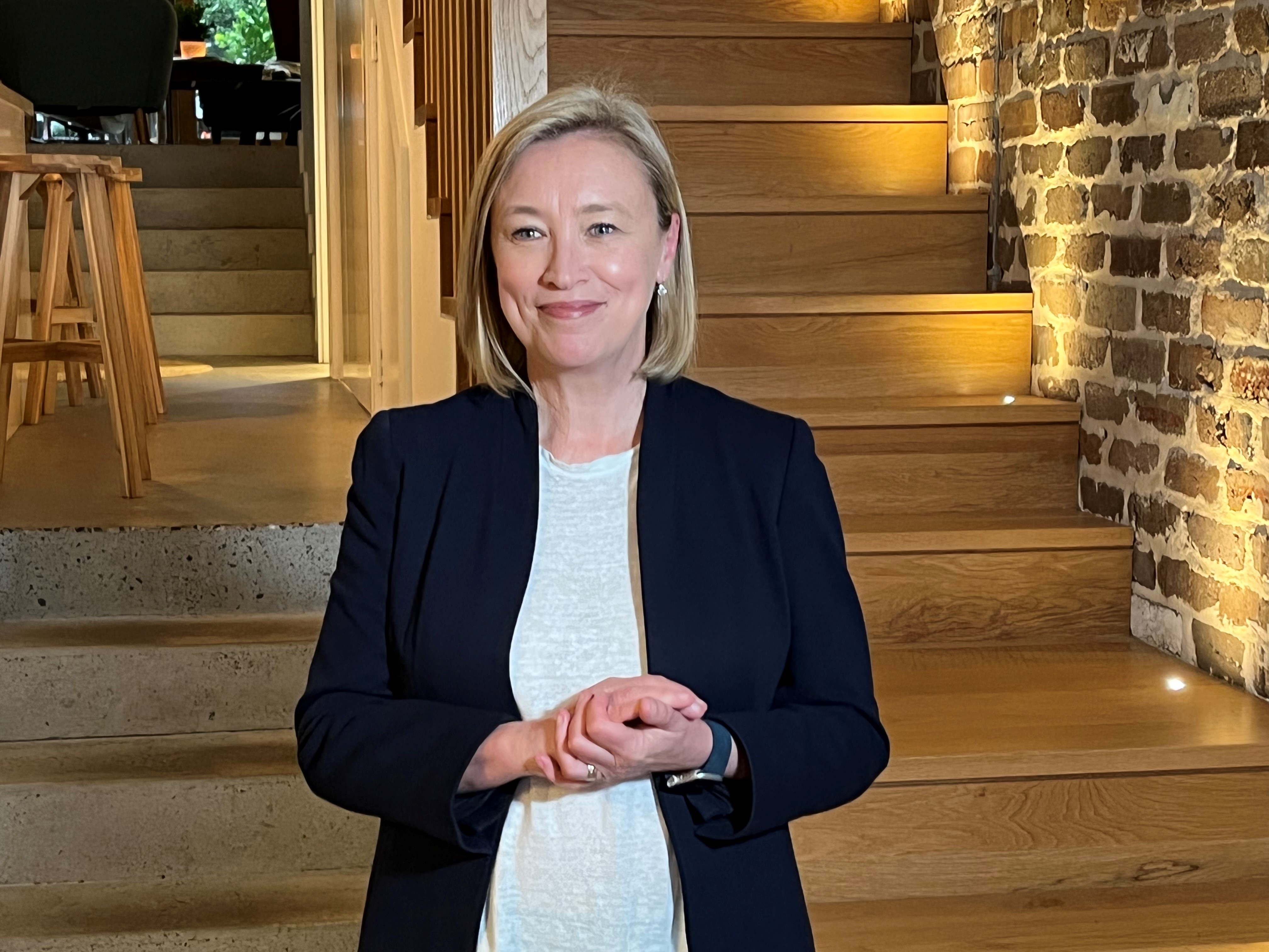 A woman with a blonde bob smiles.