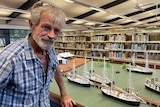 A man in a checked flannel shirt stands in front of a miniaturised version of Broome's mangroves