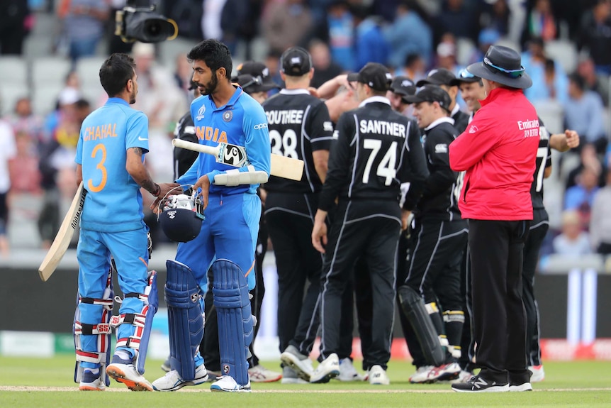 Yuzvendra Chahal and Jasprit Bumrah in the foreground with New Zealand celebrating in the background