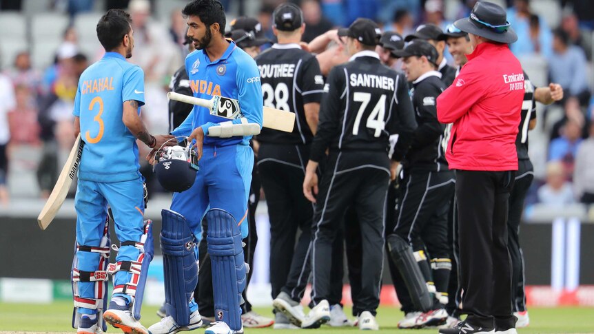 Yuzvendra Chahal and Jasprit Bumrah in the foreground with New Zealand celebrating in the background