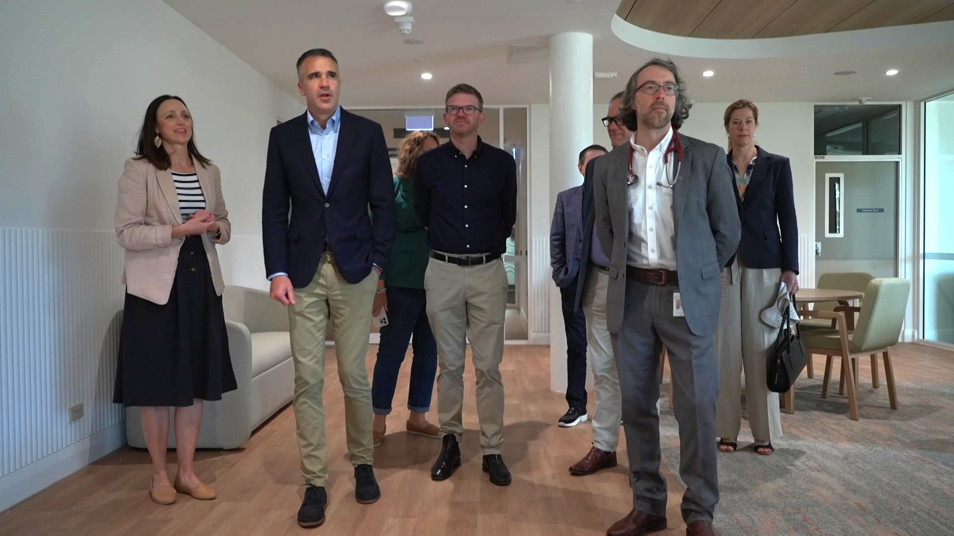 Un grupo de personas en traje de negocios recorre una sala de estar con asientos.