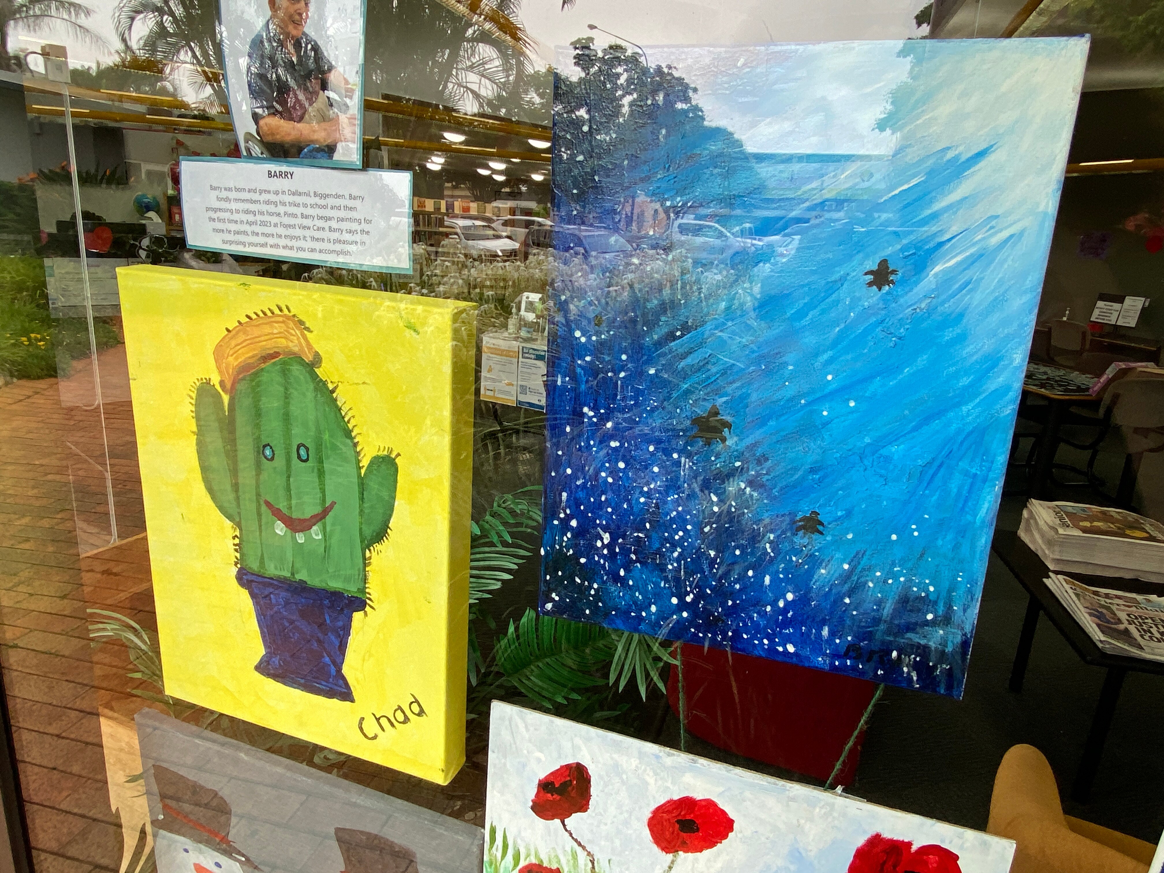 Two small bright paintings behind glass, on public display.