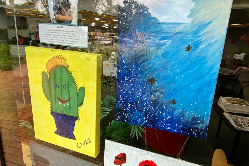 Two small bright paintings behind glass, on public display.