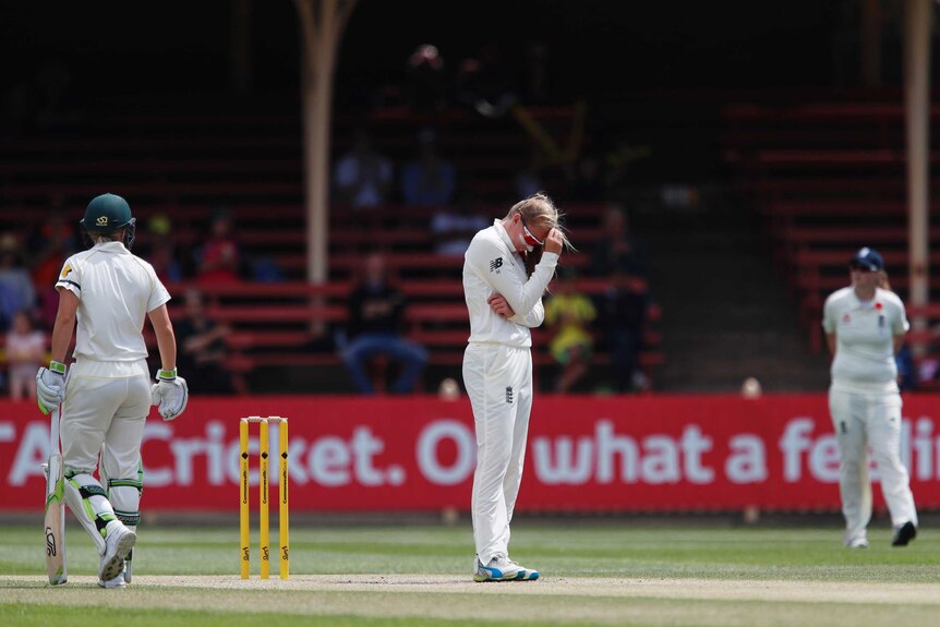 England bowler Sophie Eccleston with her right hand on her head as she looks down at the pitch against Australia.