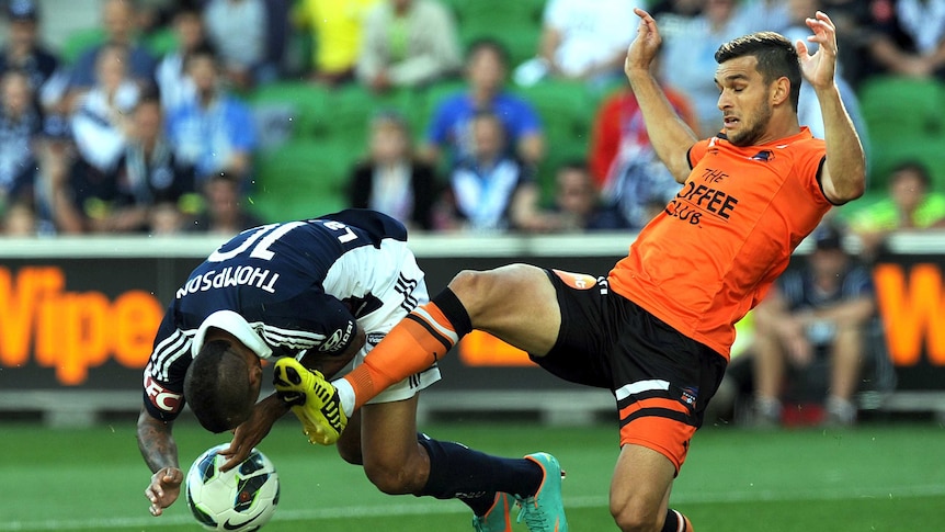 Victory's Archie Thompson is fouled by Brisbane Roar's Jack Hingert.