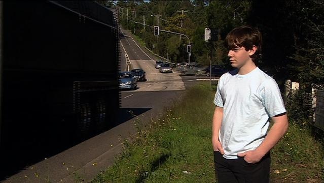 A boy stands beside a major road