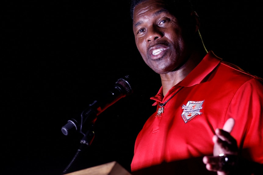 A close up for Herschel Walker speaking into a microphone. 