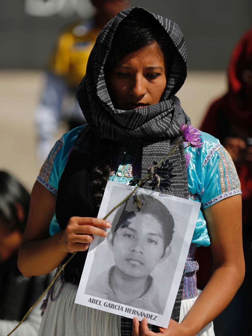 A demonstrator holds a picture of a missing student in Mexico.jpg