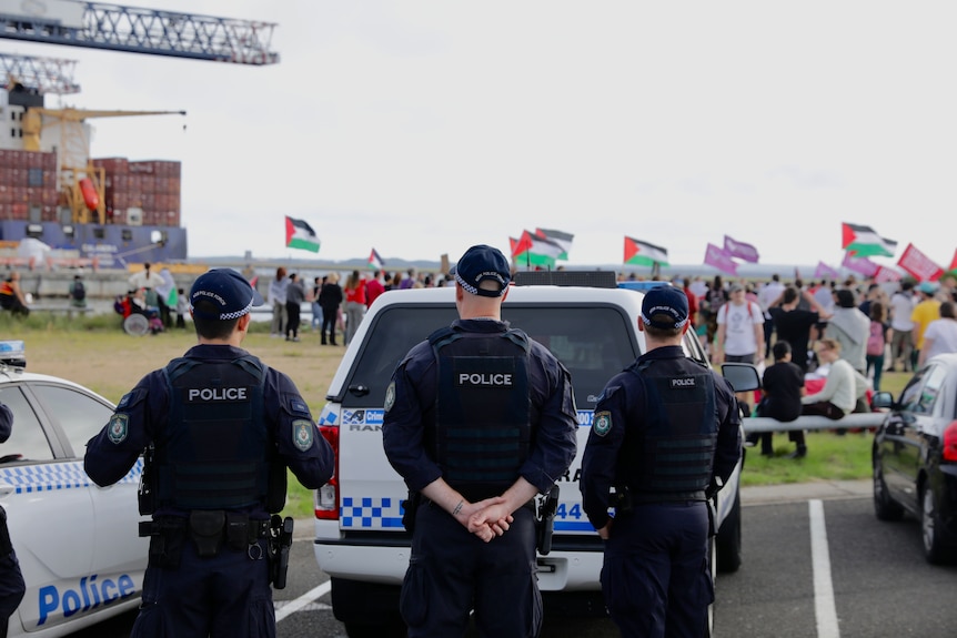 Police overlook a gathering in Port Botany with protesters holding Palestinian flags
