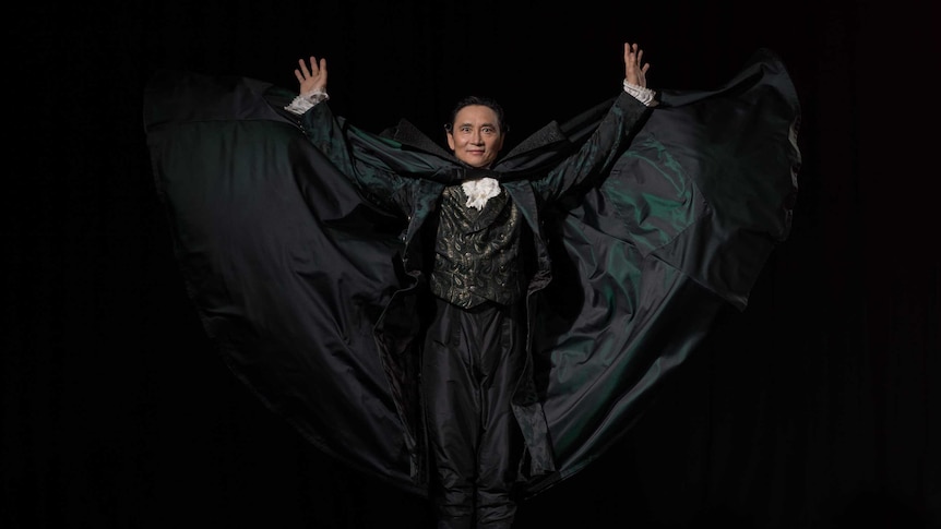 Li Cunxin in cape with arms outstretched dressed as Drosselmeyer in the Nutcracker