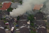 An aerial shot of a Murrumba Downs neighbourhood shows emergency crews on scene and smoke billowing from a home
