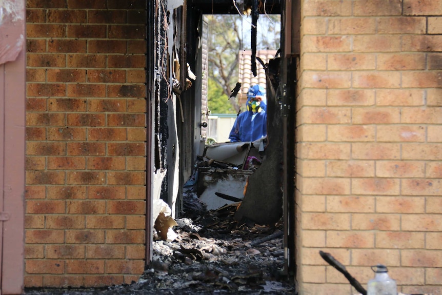 A forensics team member probes the scene.