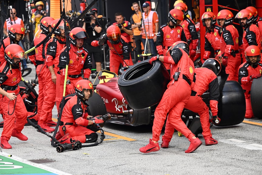 Ferrari mechanics putting tyres on their F1 car