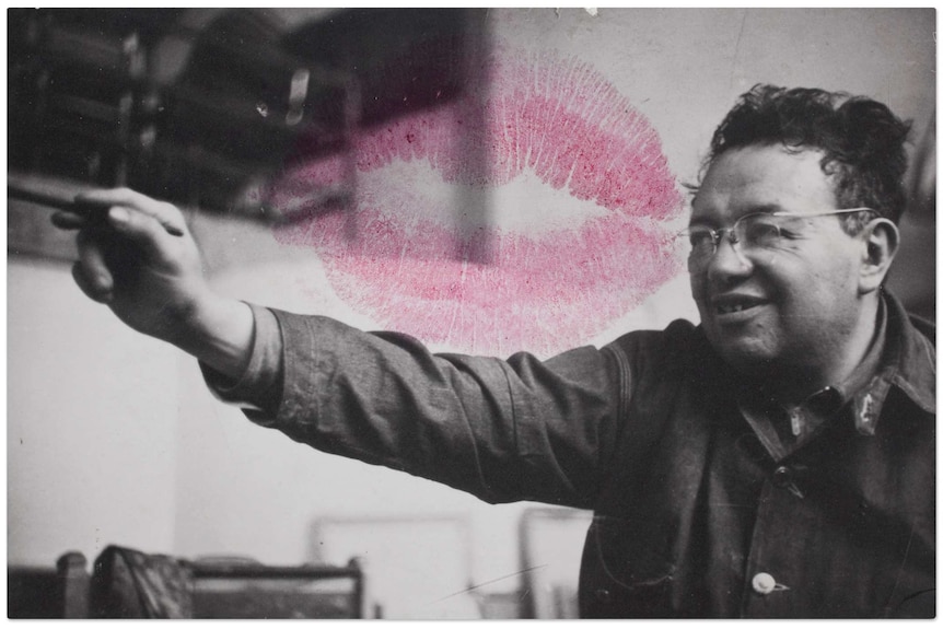 An black and white photo of Diego Rivera painting is embellished with the red lipstick mark left by Frida Kahlo's kiss.