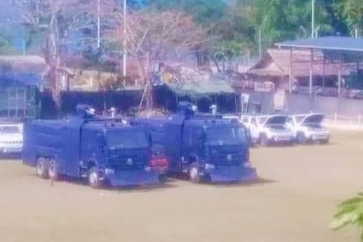 Water cannon police trucks in a compound. 