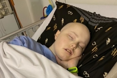 A teenage cancer patient sleeps in a bed.
